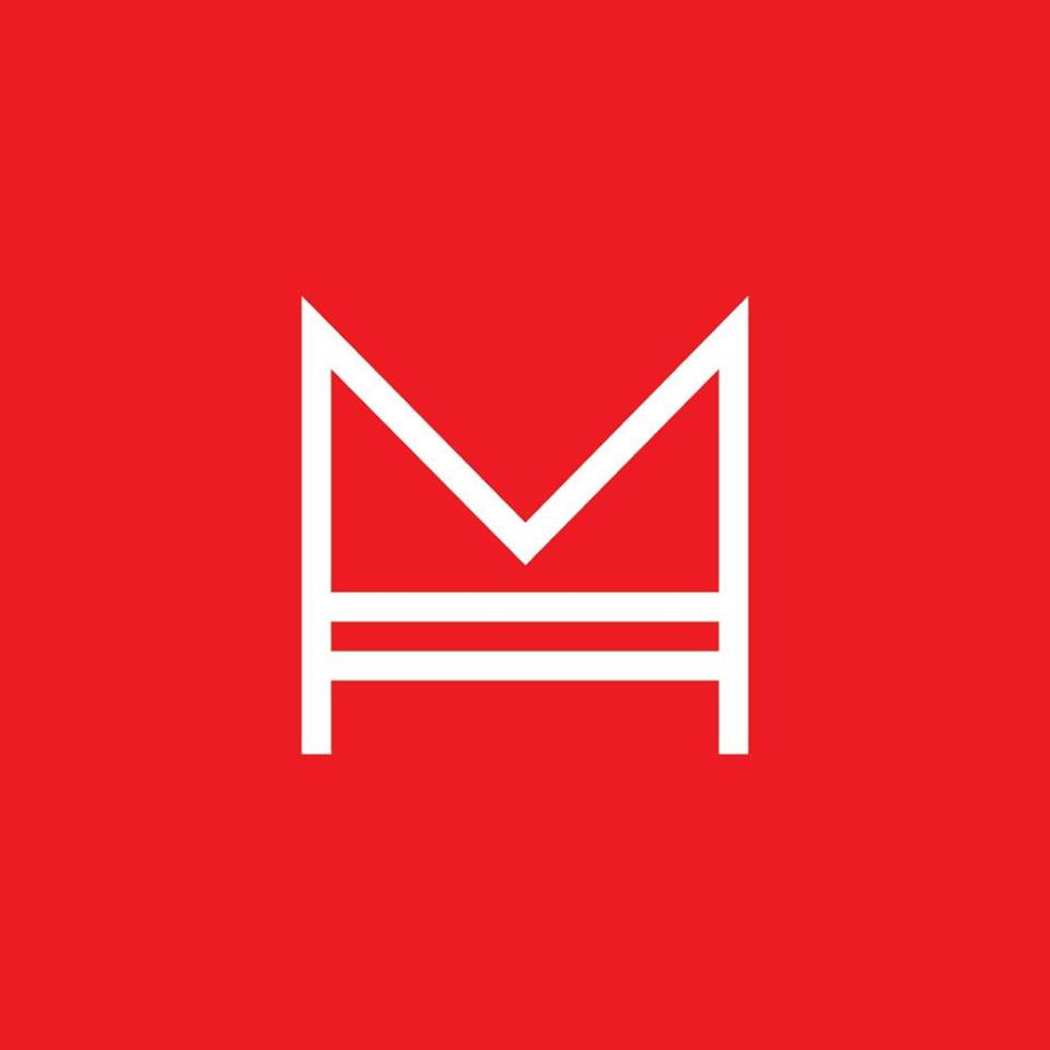 This logo consists of a bright red square, which has, in the middle, a white outline of a capital "M" with two horizontal lines connecting the interior vertical lines of the "M."